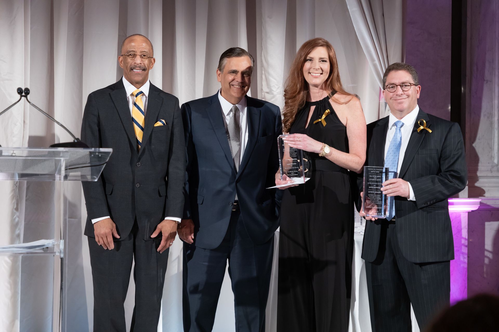 A group of people standing next to each other on a stage holding awards.