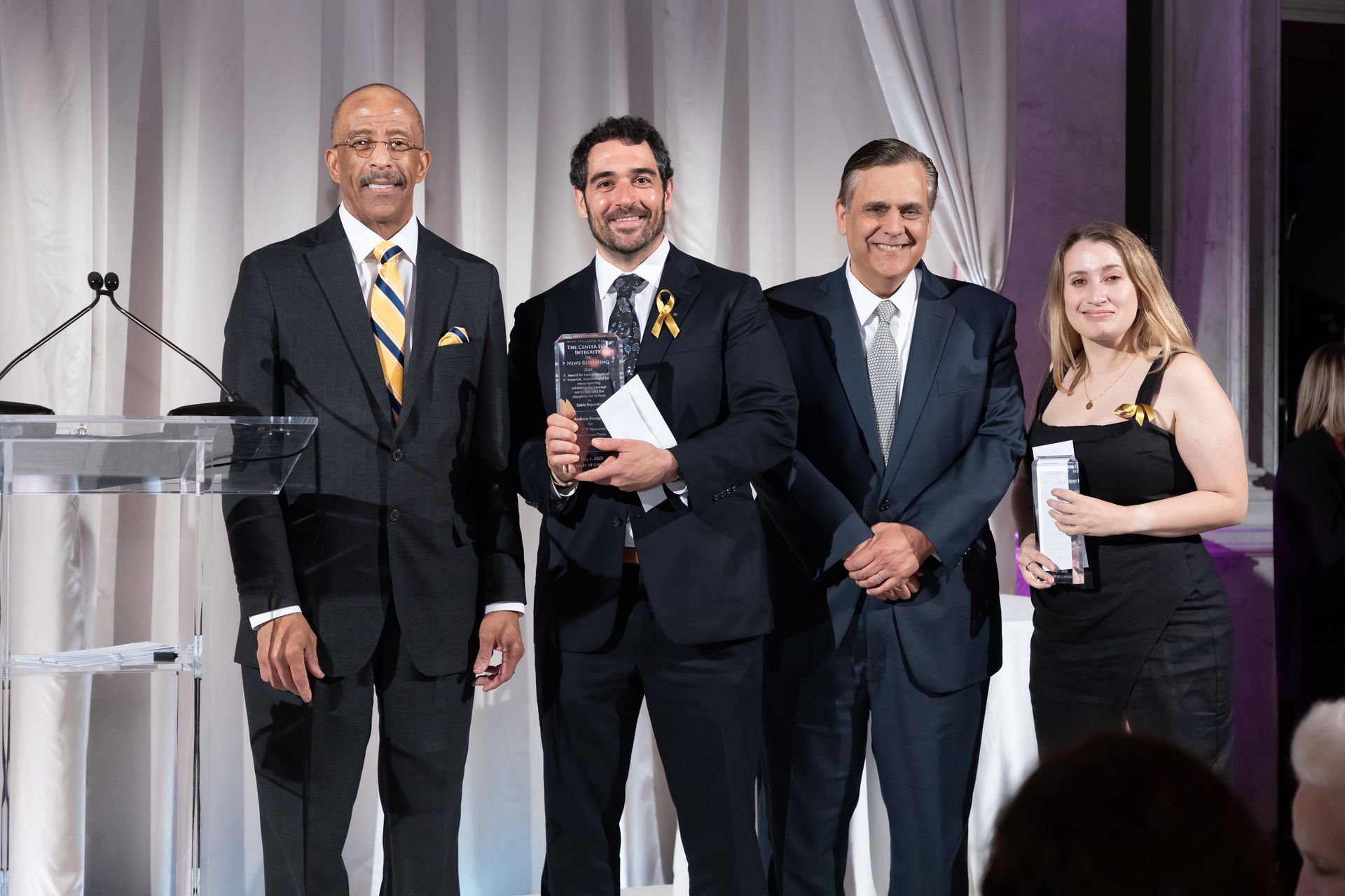 A group of people in suits and ties are standing next to each other holding awards.