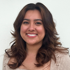 A woman with long brown hair is smiling for the camera.