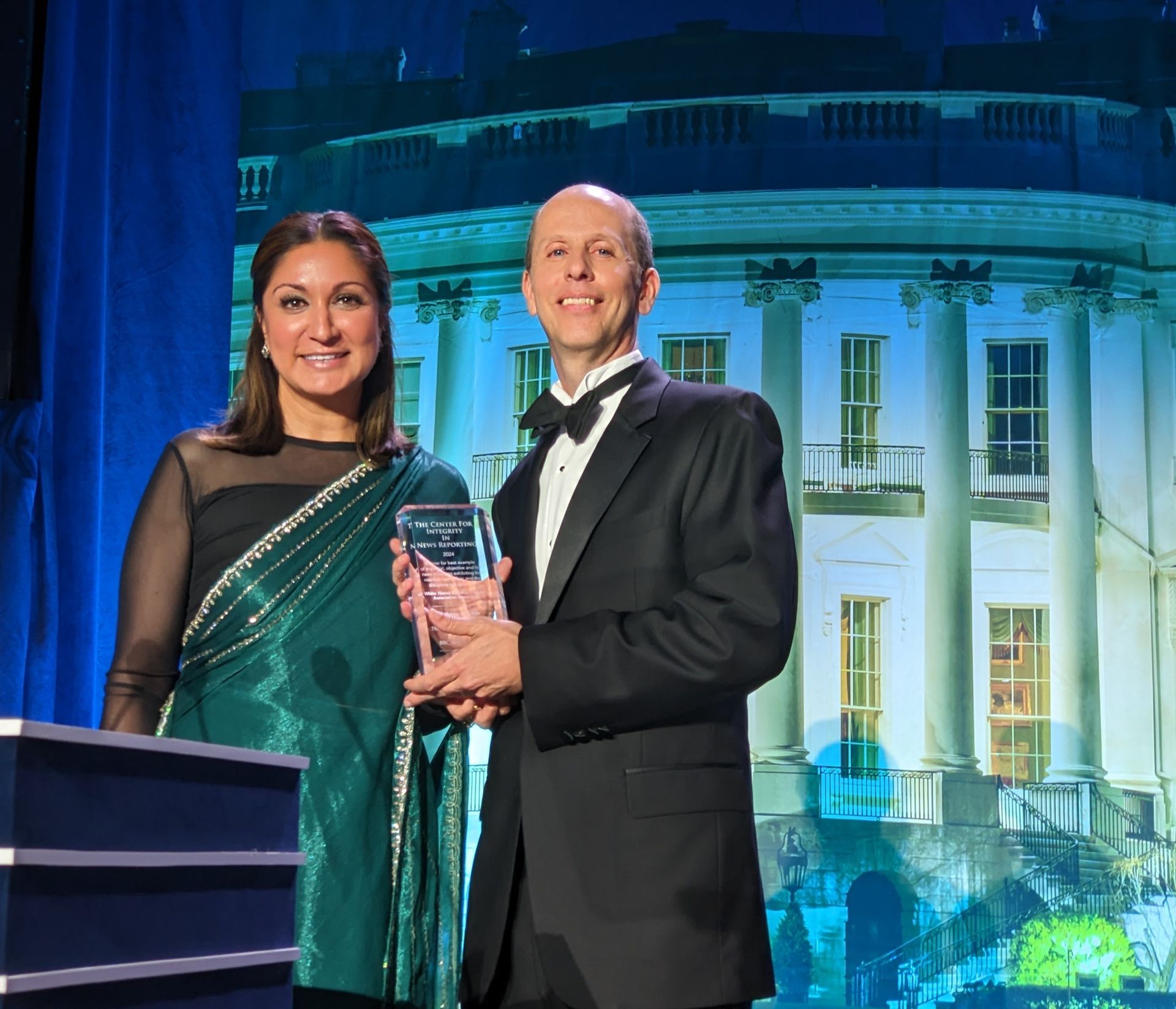 A man and a woman are standing in front of a white house
