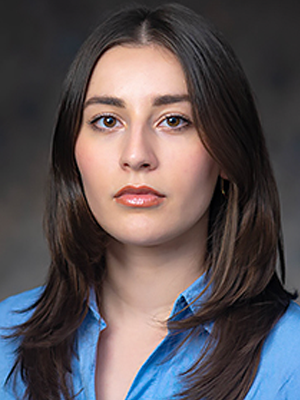 The woman is wearing a blue shirt and looking at the camera.