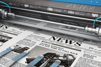 A close up of a newspaper being printed on a machine.