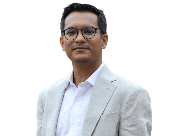 A man wearing glasses and a suit is standing in front of a white background.