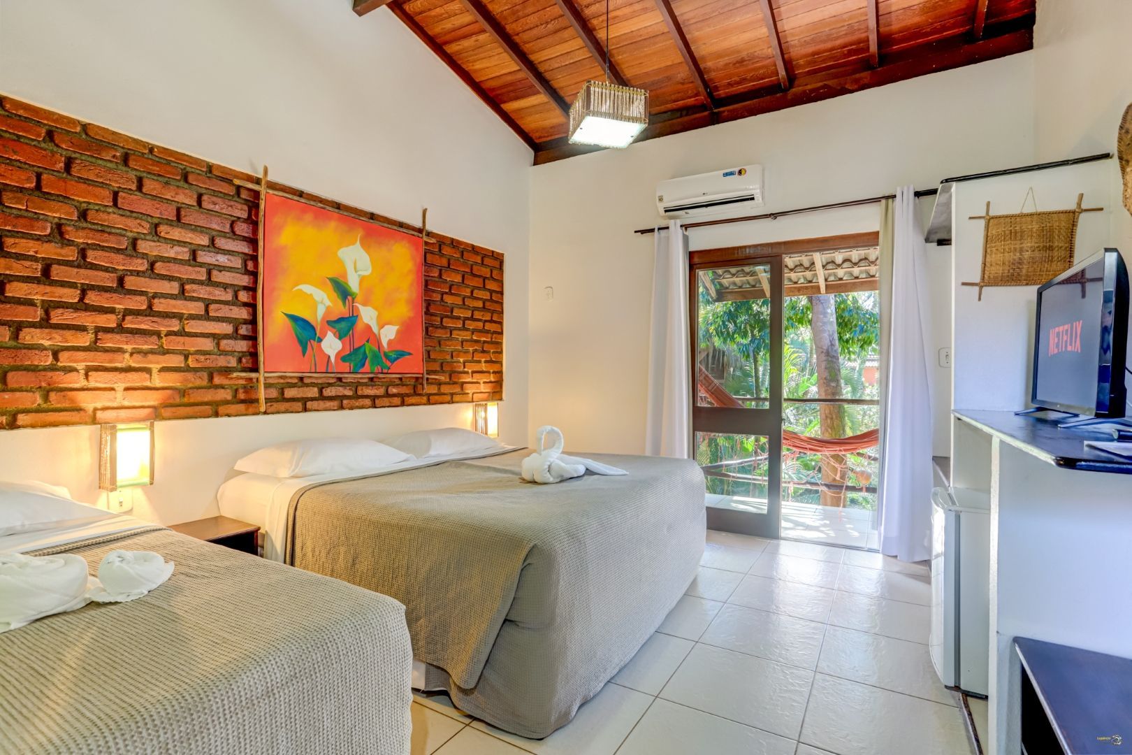 Um quarto de hotel com três camas e uma televisão.