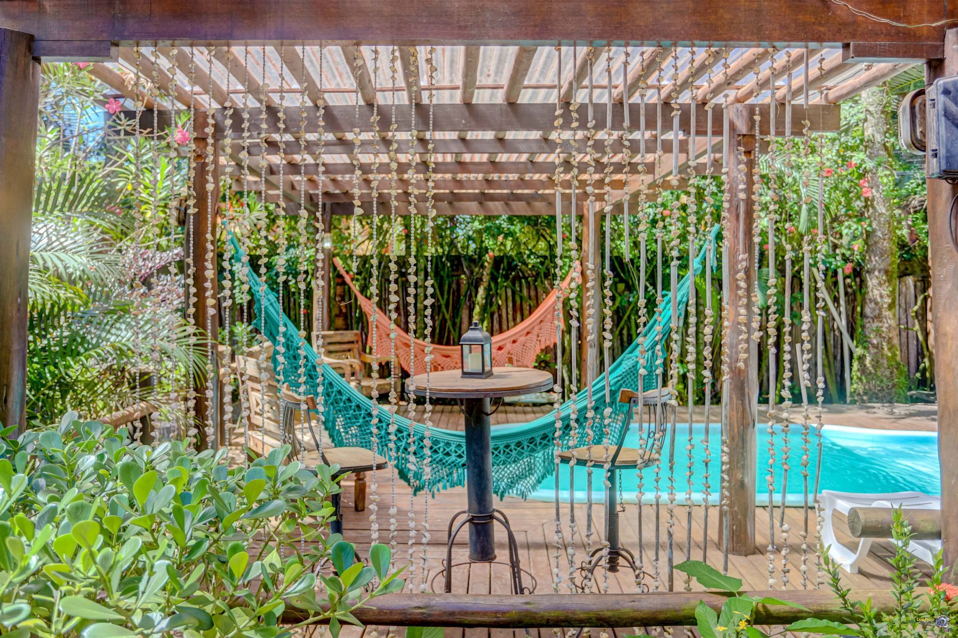 Uma rede está sob uma pérgola ao lado de uma piscina.