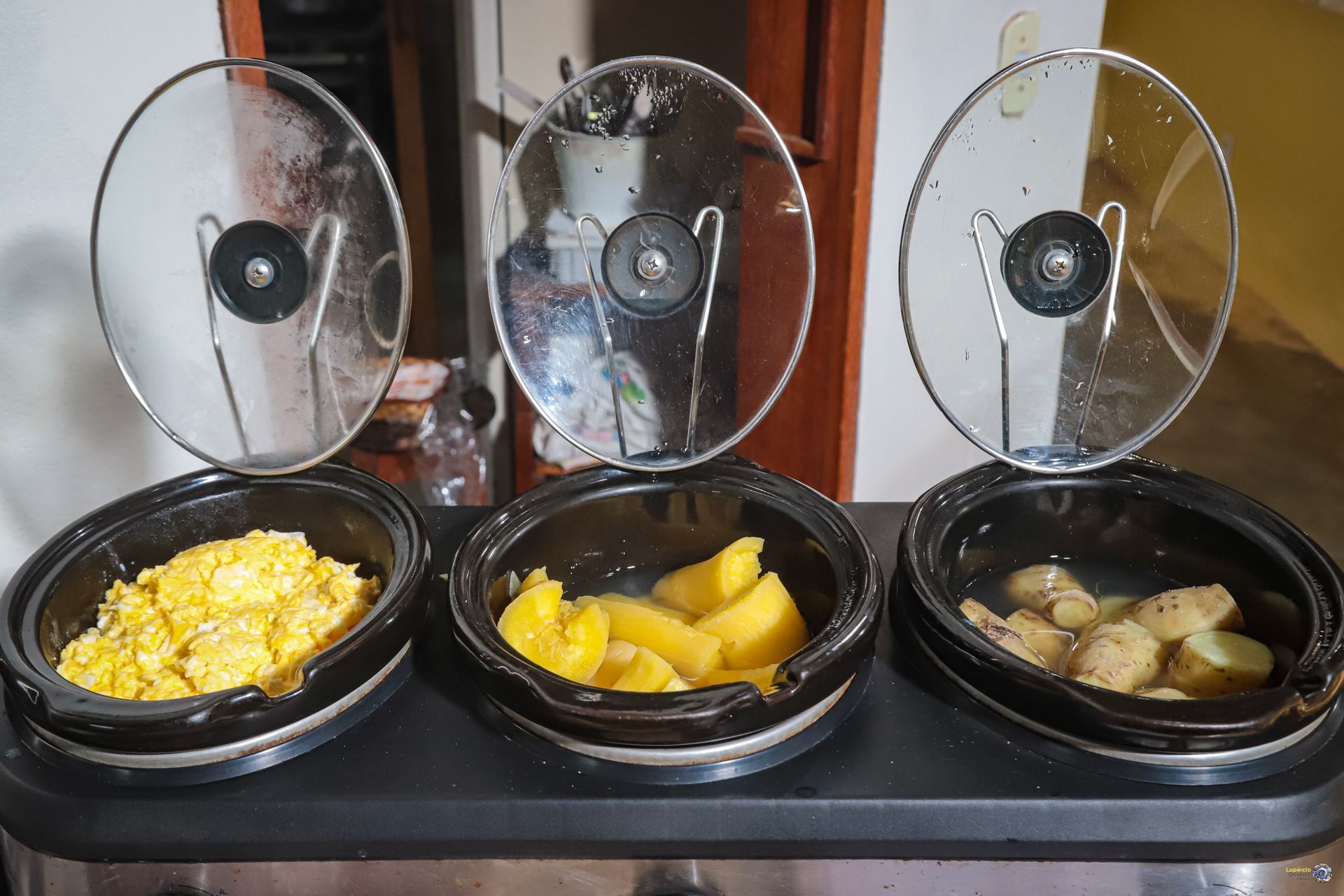 Três tigelas de comida estão sobre uma mesa com as tampas abertas.