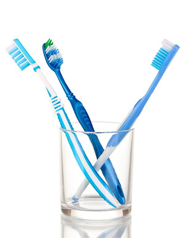 Clear glass with three toothbrushes in it
