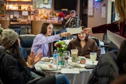 A group of people are sitting around a table in a restaurant — Lafayette, CO — Clean Conscience