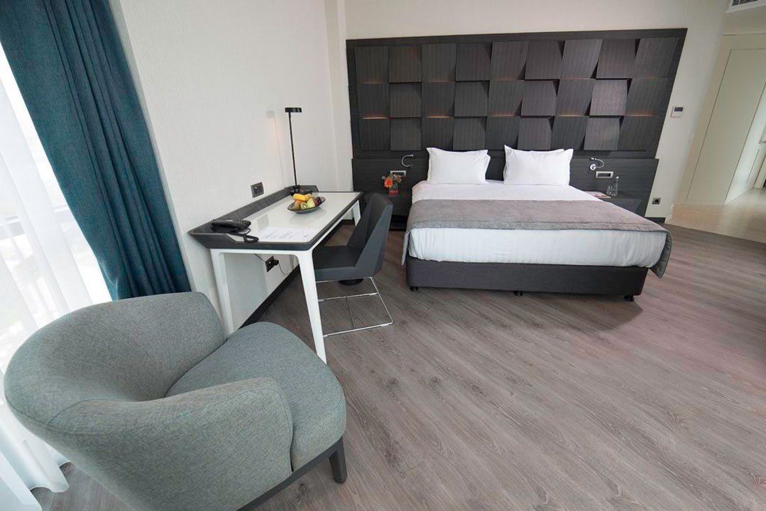 A hotel room with a bed , chair , desk and window.