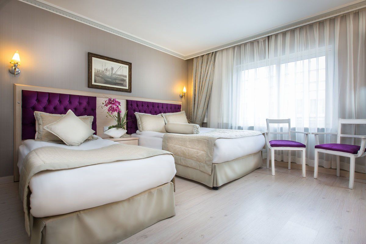 A hotel room with two beds and two chairs.