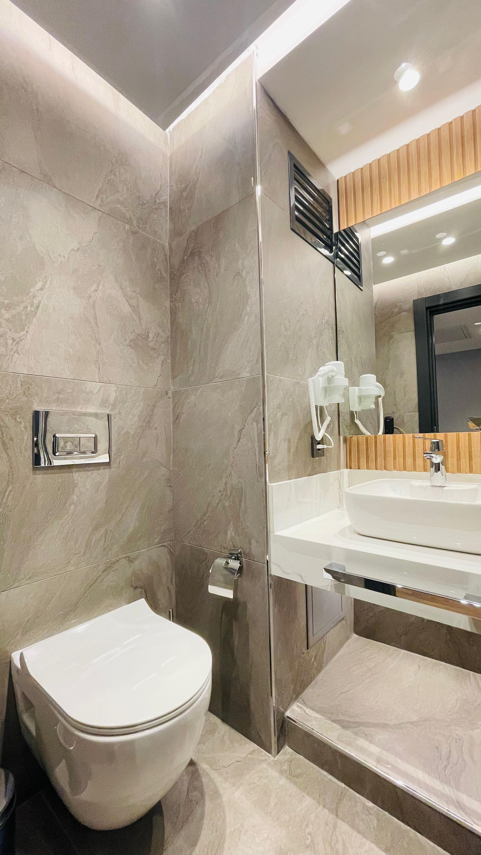 A bathroom with a toilet , sink and mirror.