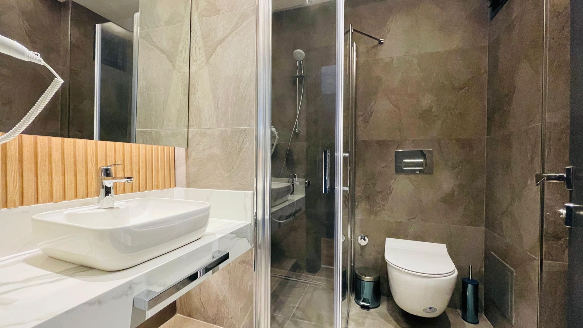 A bathroom with a sink , toilet , shower and mirror.