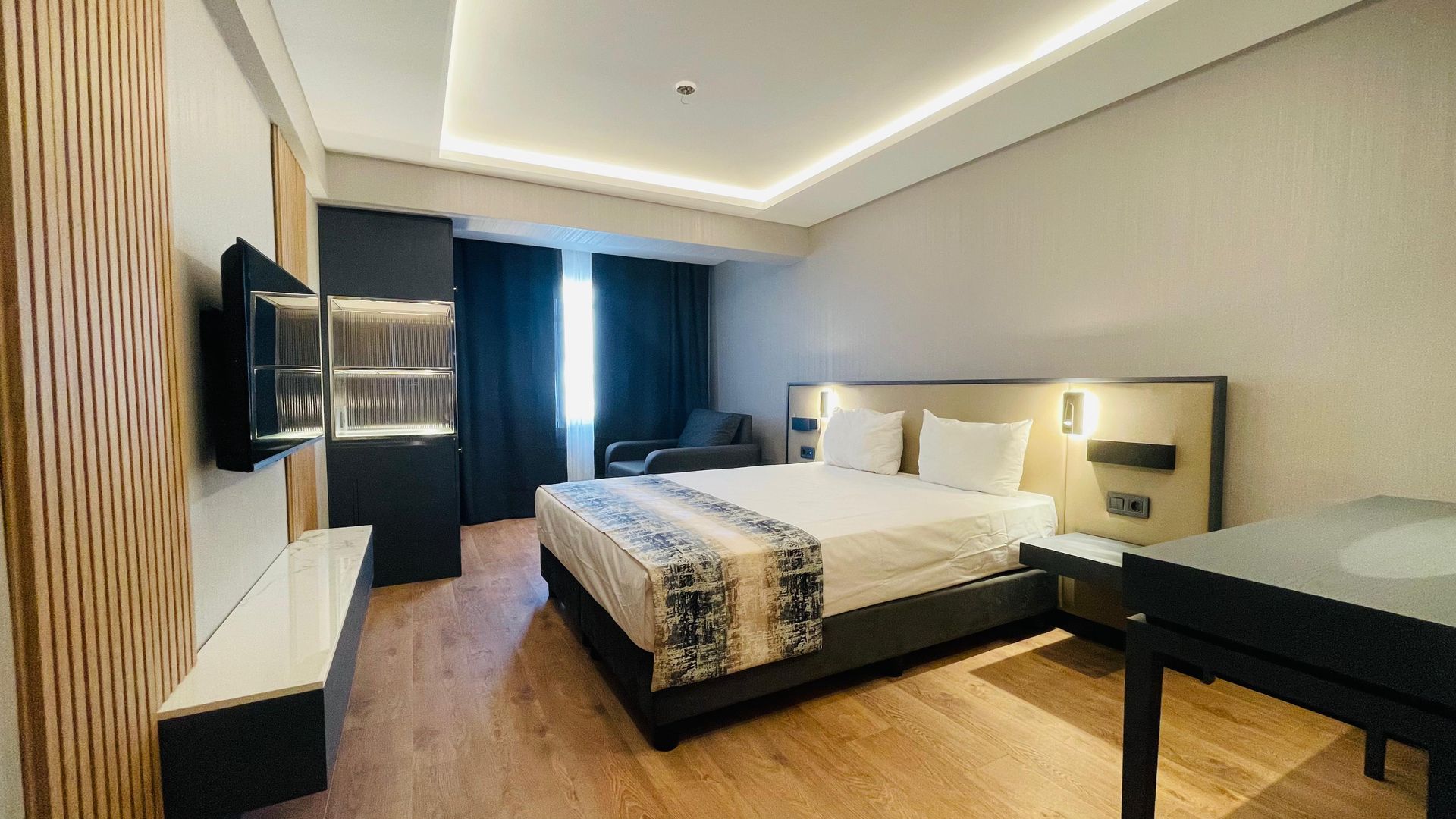 A hotel room with a king size bed and a desk.