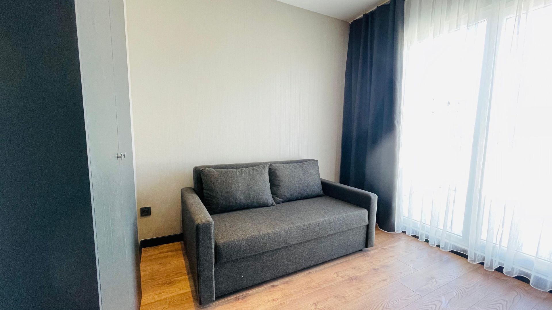 A couch is sitting in a living room next to a window.