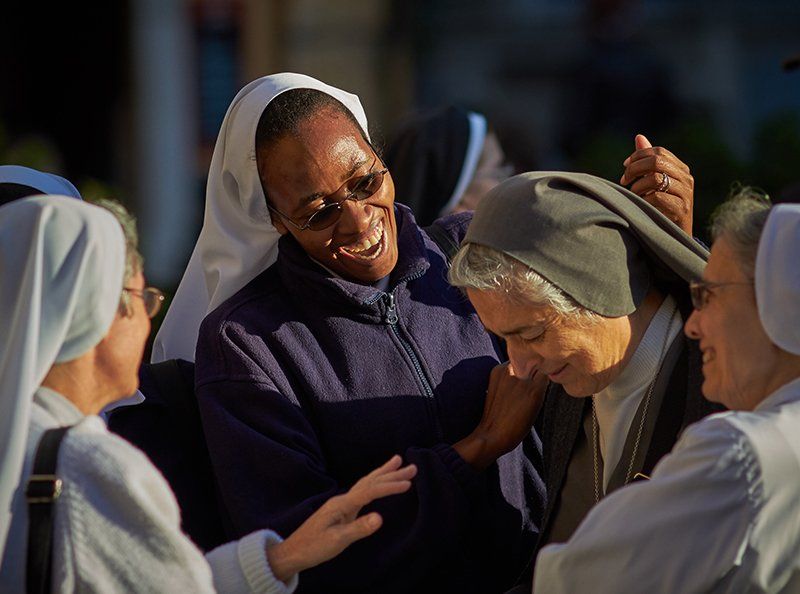 A group of nuns are laughing and hugging each other.