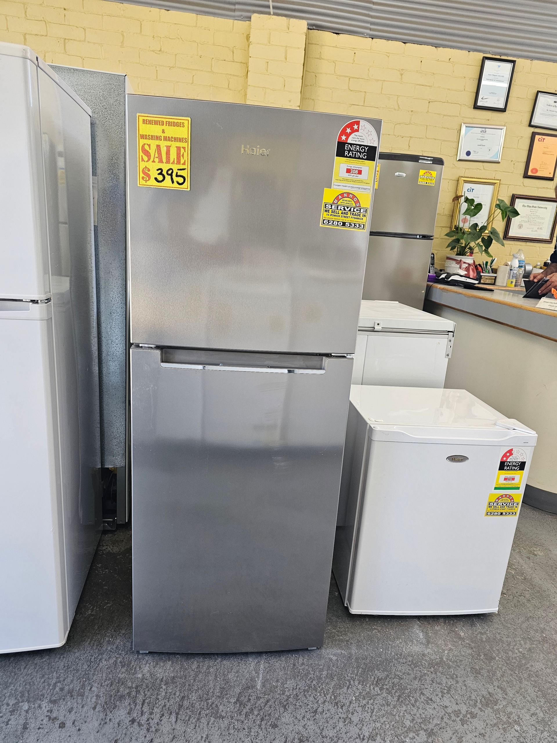 A stainless steel refrigerator with a sale sign on it