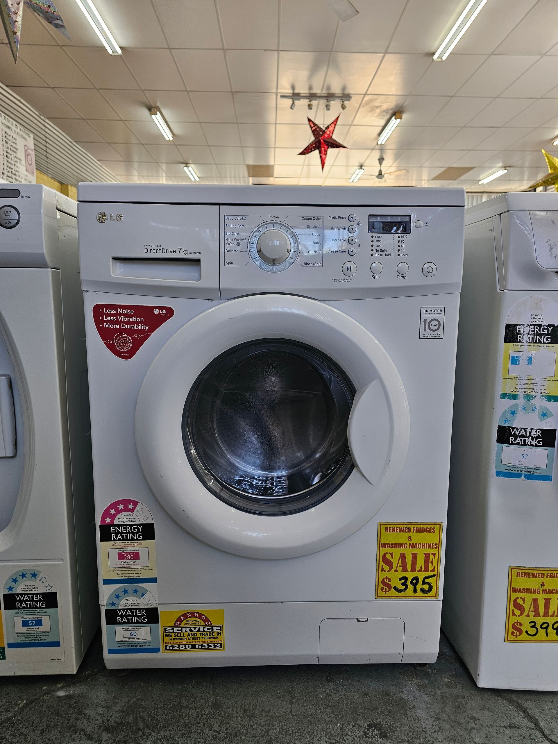 A white washing machine is sitting in a room with other washing machines.