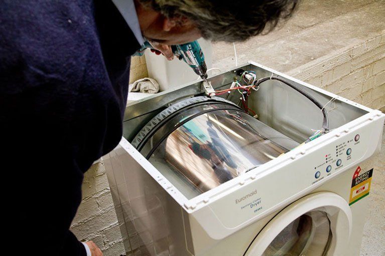 Man Fixing Washing Machine — Canberra, ACT — Renewed Appliances - Manhos