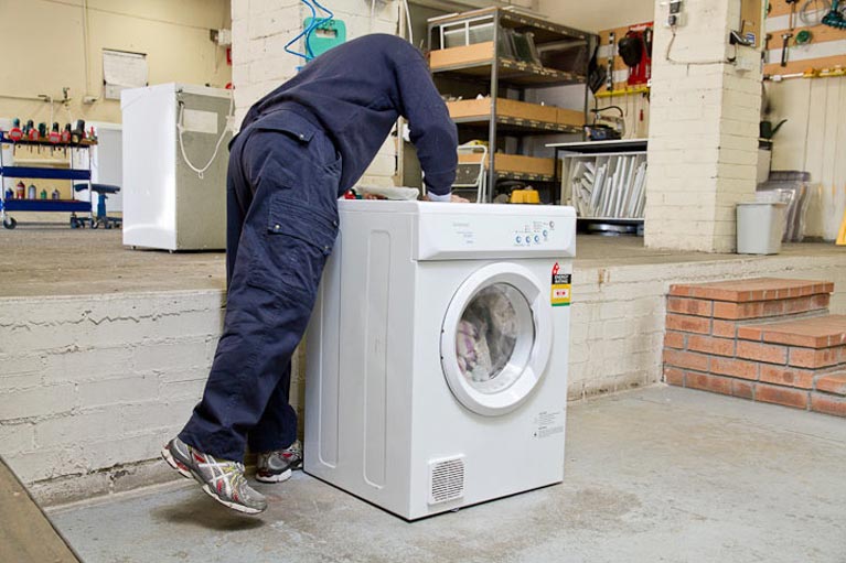 Man Inspecting Washing Machine — Canberra, ACT — Renewed Appliances - Manhos