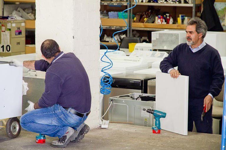 Men Working on Washing Machines — Canberra, ACT — Renewed Appliances - Manhos