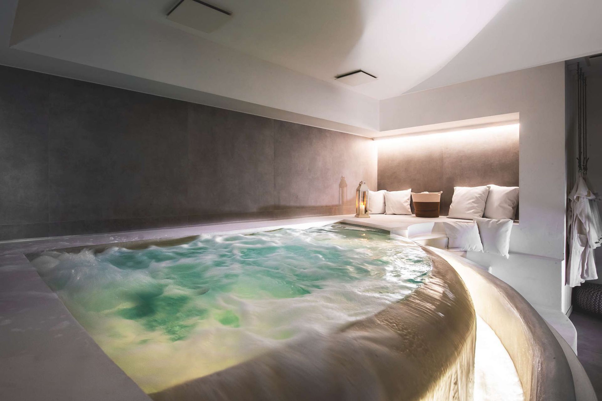 Una lussuosa spa con vasca idromassaggio e area salotto, illuminata da una luce calda.