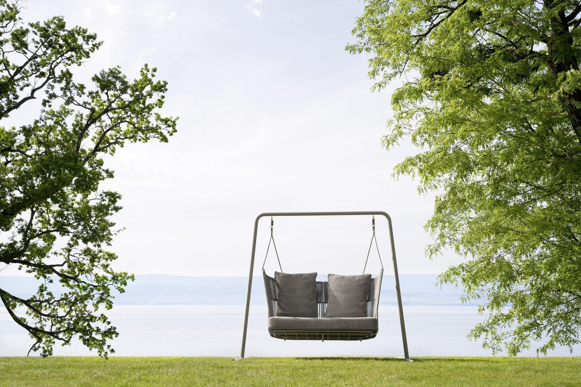 Altalena su una collina erbosa con vista su un lago, incorniciata da alberi.
