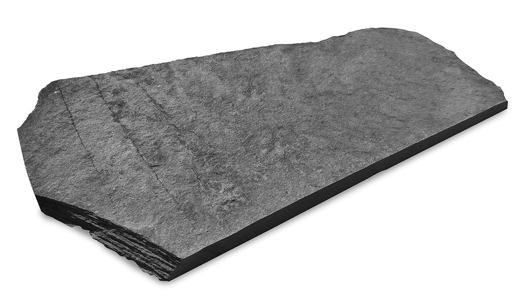 Piastrella rettangolare in pietra grigio scuro, leggermente curva. Bordi sovrapposti, angolati.