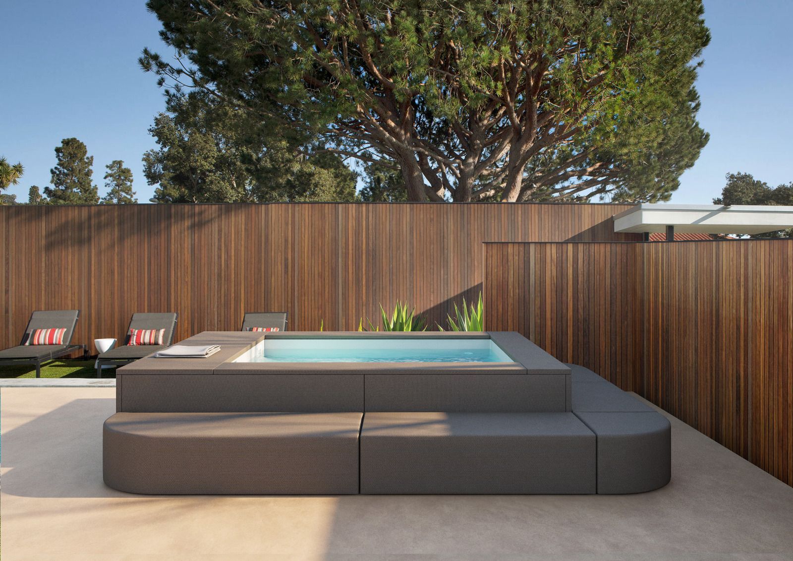 Moderna spa all'aperto con posti a sedere integrati, recinzione in legno e grande albero.