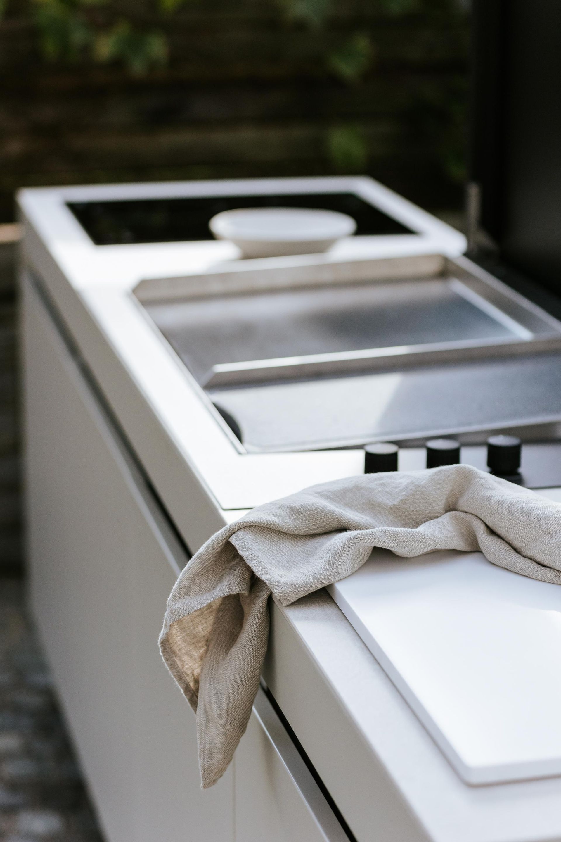 Griglia in acciaio inox e piano di lavoro con asciugamano, all'aperto.