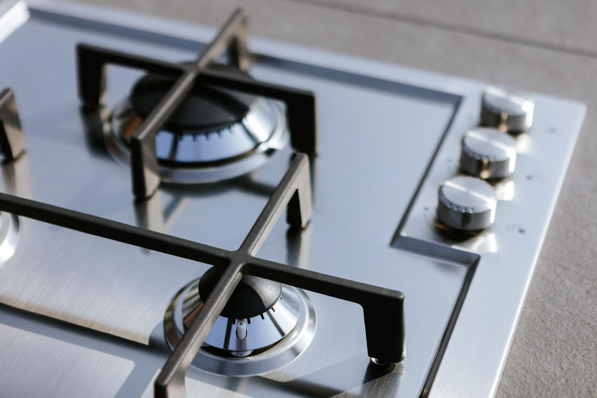 Piano cottura a gas in acciaio inox con bruciatori accesi e manopole di controllo.