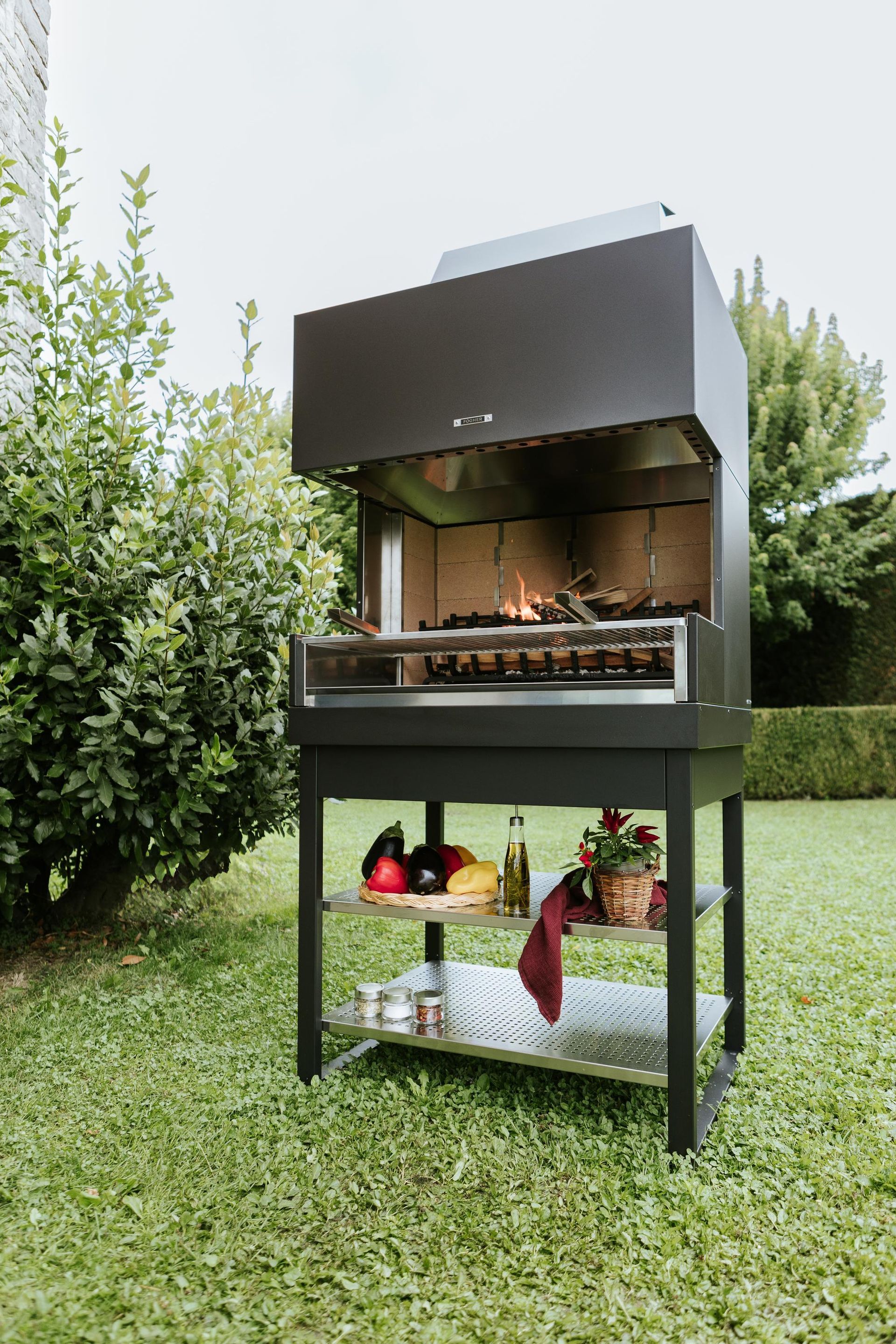 Barbecue a carbone da esterno con cibo su ripiani, in un ambiente da giardino.