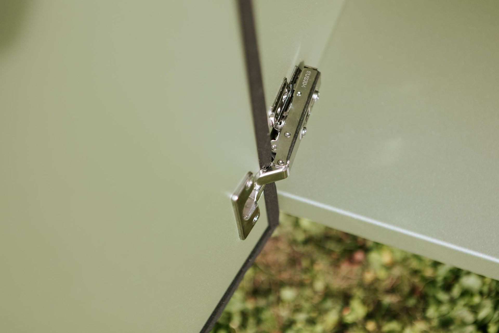 Cerniera argentata che collega due pannelli verde chiaro.
