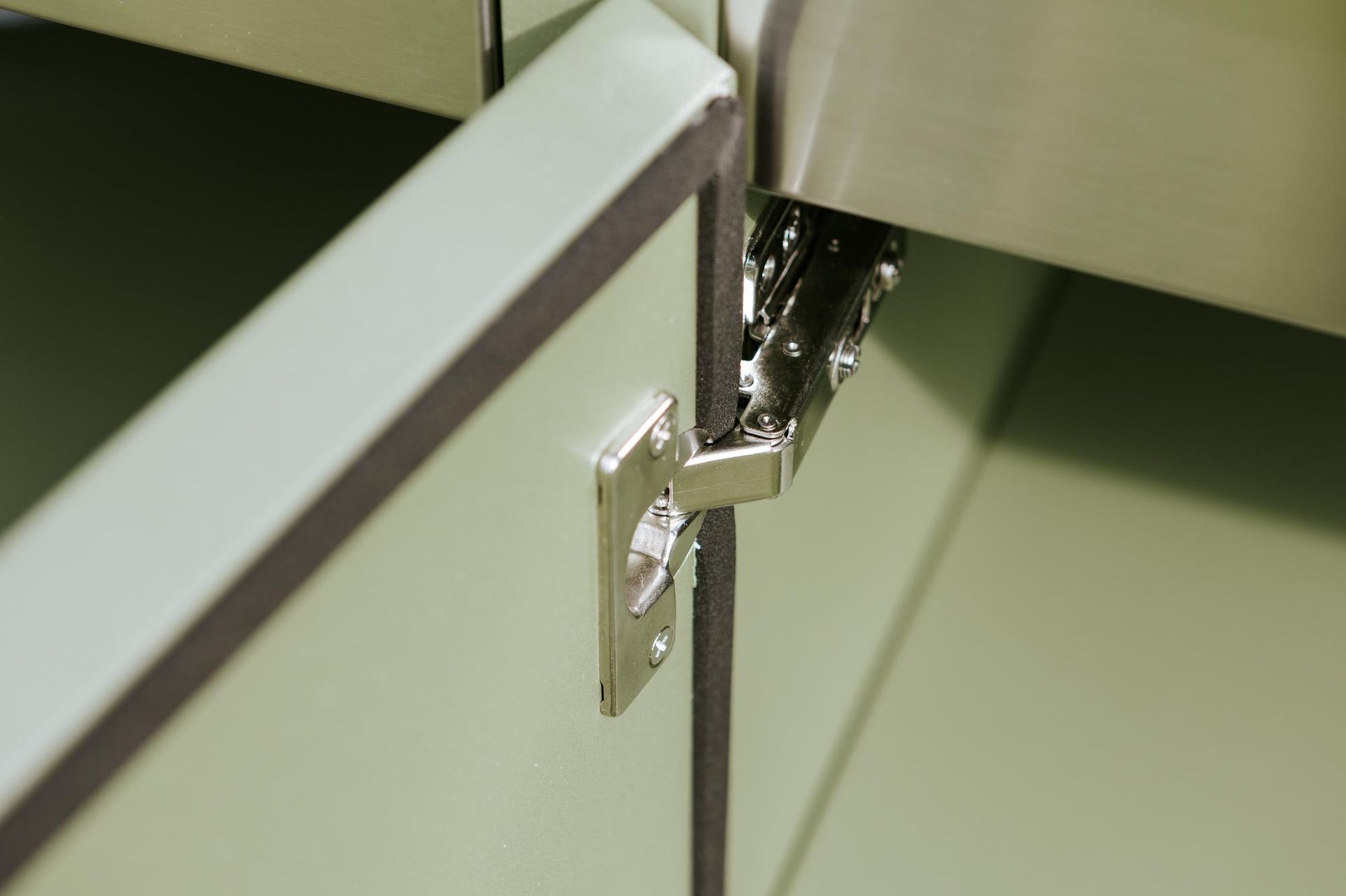 Cerniera per mobiletto argentata su mobiletto verde.