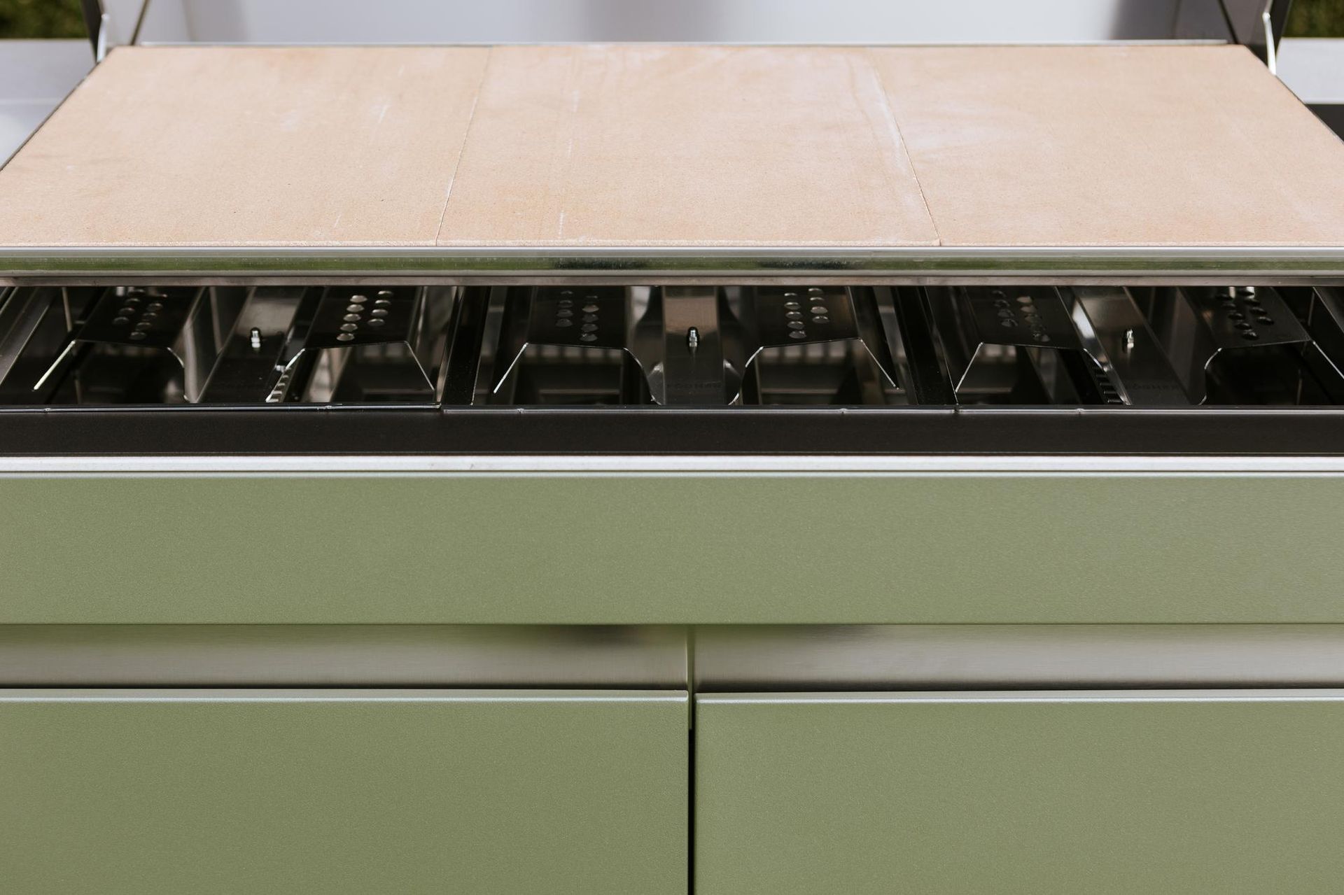 Primo piano di una griglia da esterno verde chiaro con piano di lavoro in legno.