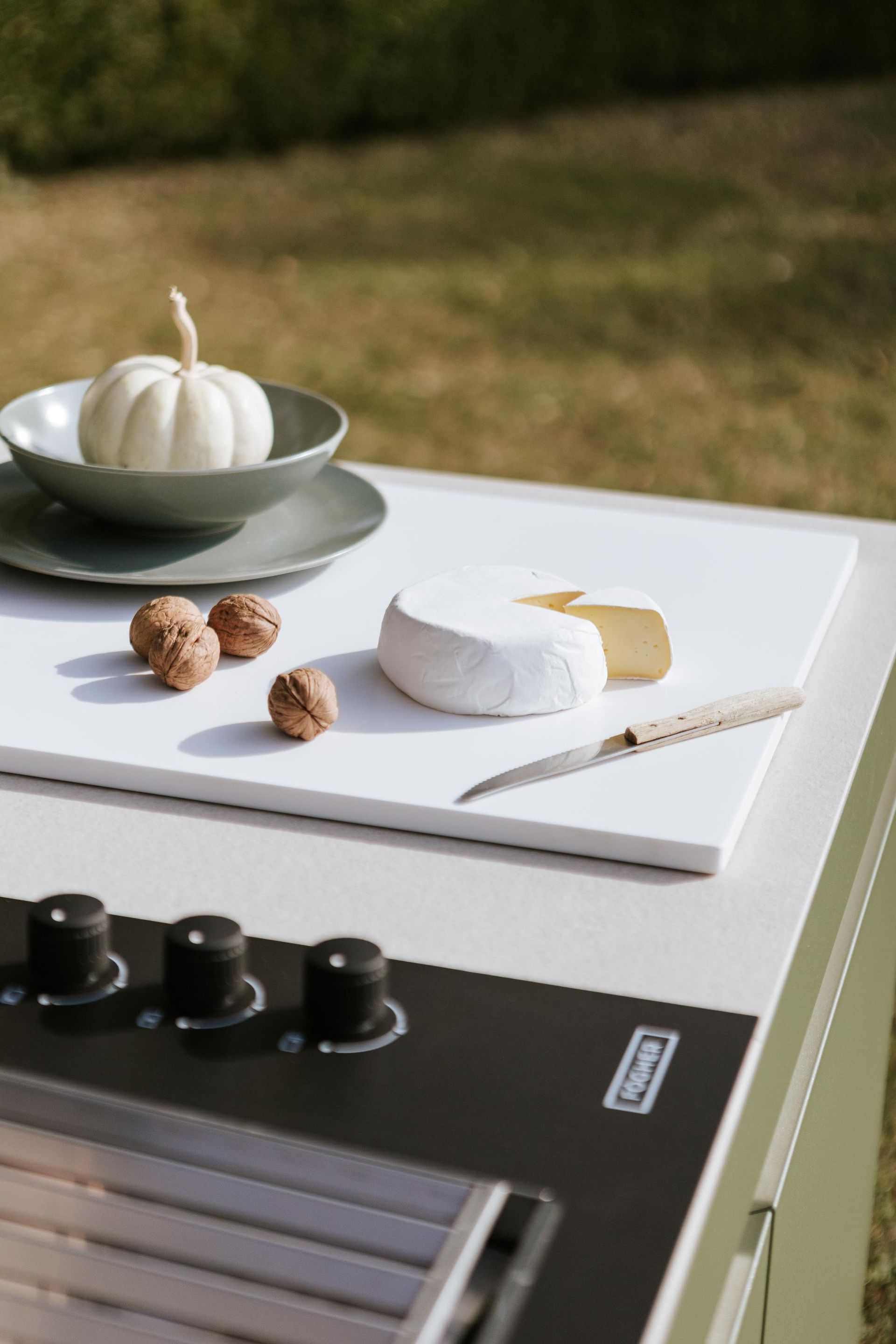 Formaggio brie bianco, noci e una piccola zucca su un tagliere sopra una griglia.