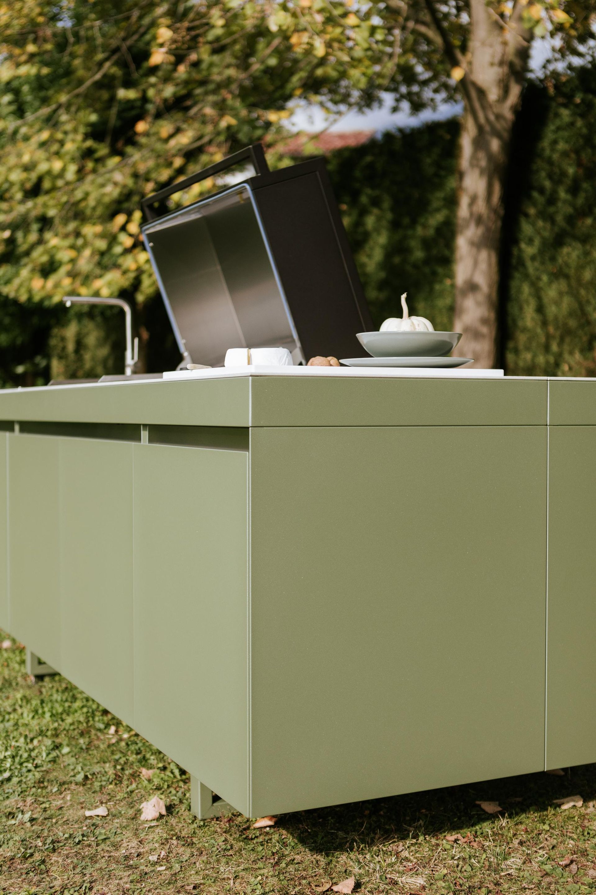 Cucina verde all'aperto su erba con elettrodomestici in acciaio inossidabile.