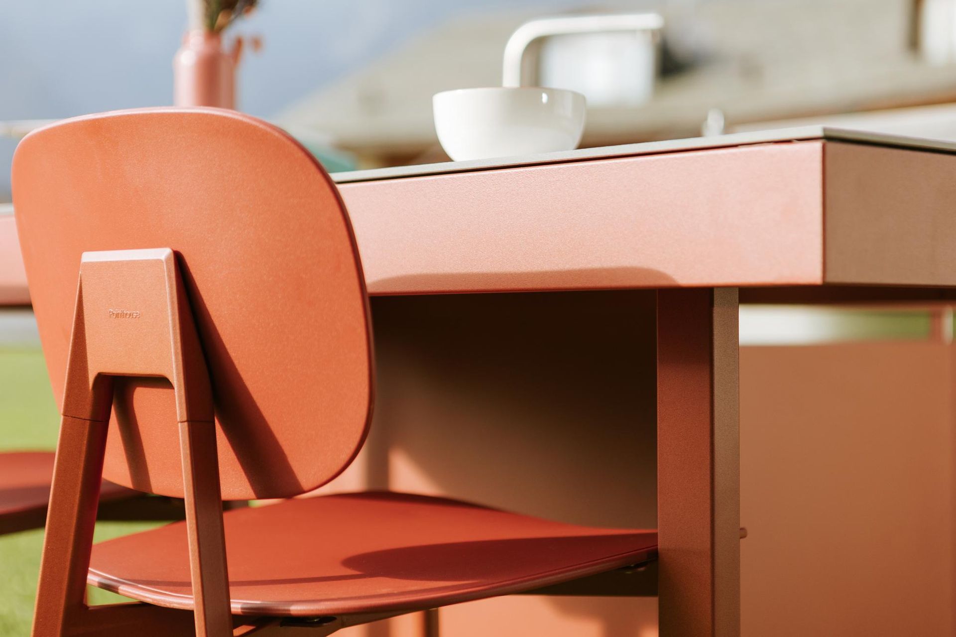 Sedia arancione su un bancone coordinato con una ciotola bianca e un rubinetto.