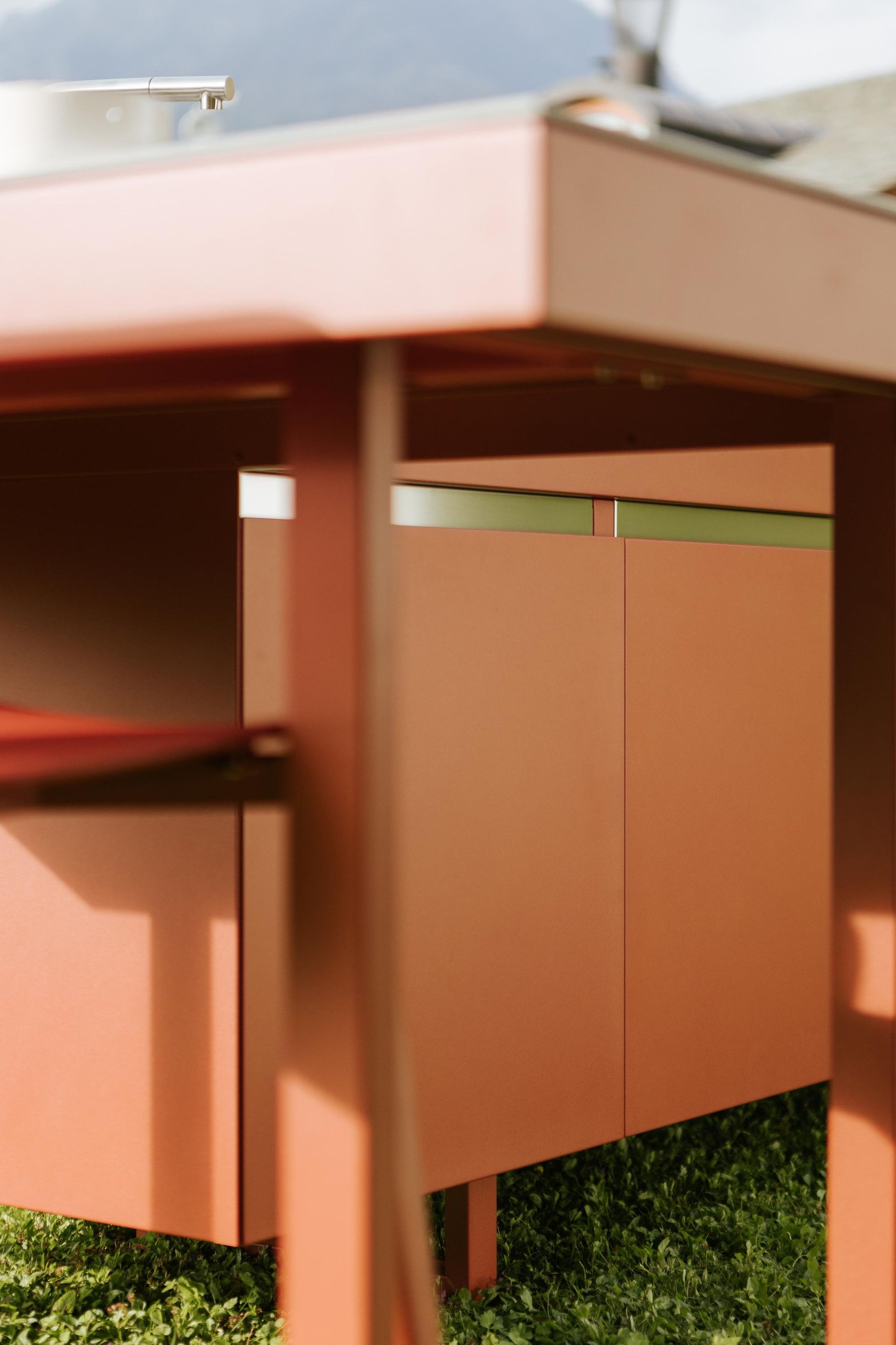 Mobiletto da cucina rosso da esterno con erba sottostante.