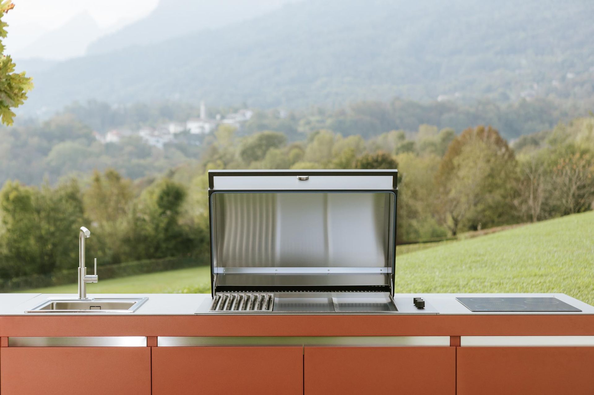 Cucina esterna con griglia, lavello e piano cottura, con vista sul paesaggio montano.