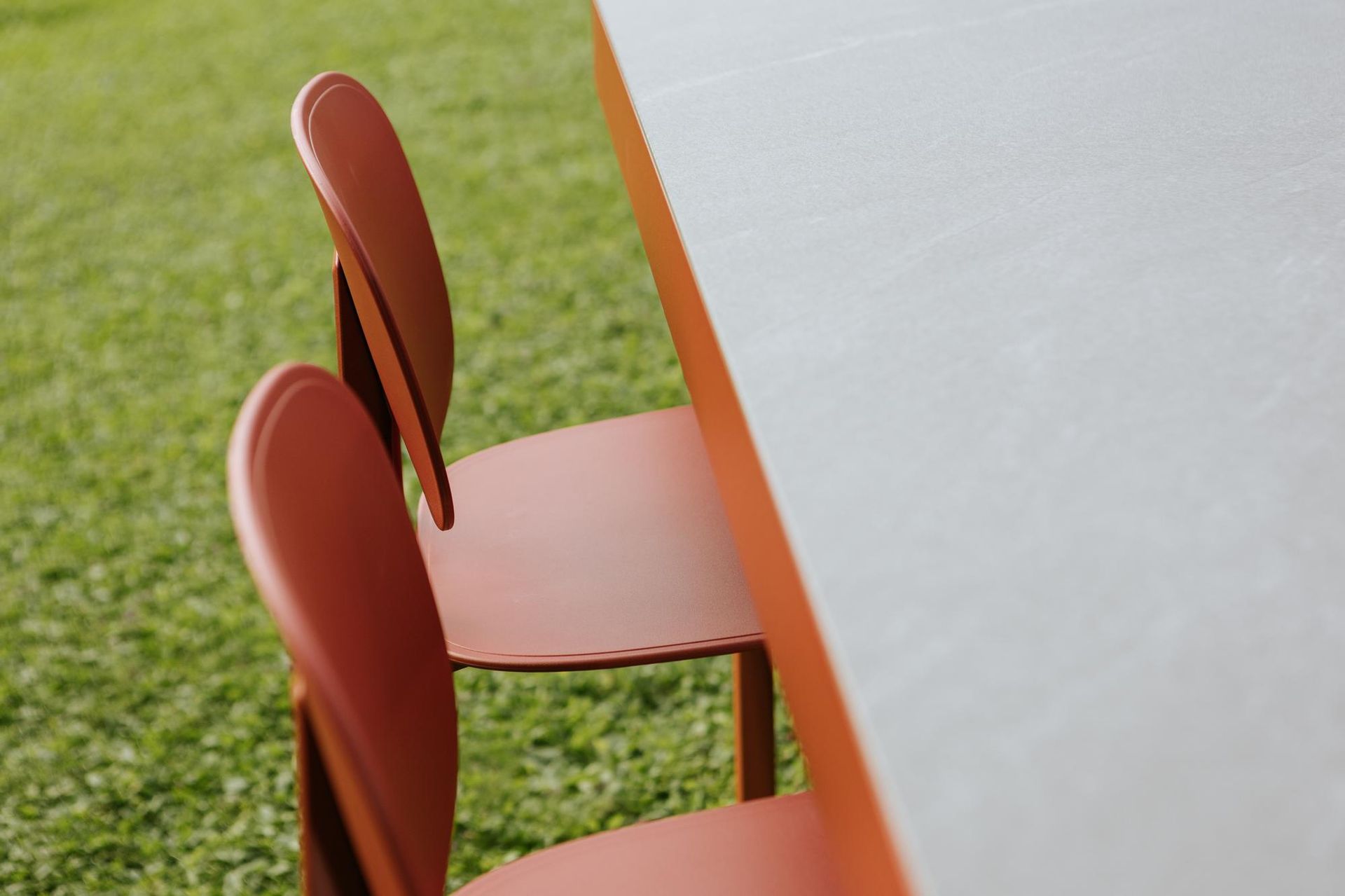 Sedie arancioni accanto a un tavolo bianco su un prato verde.