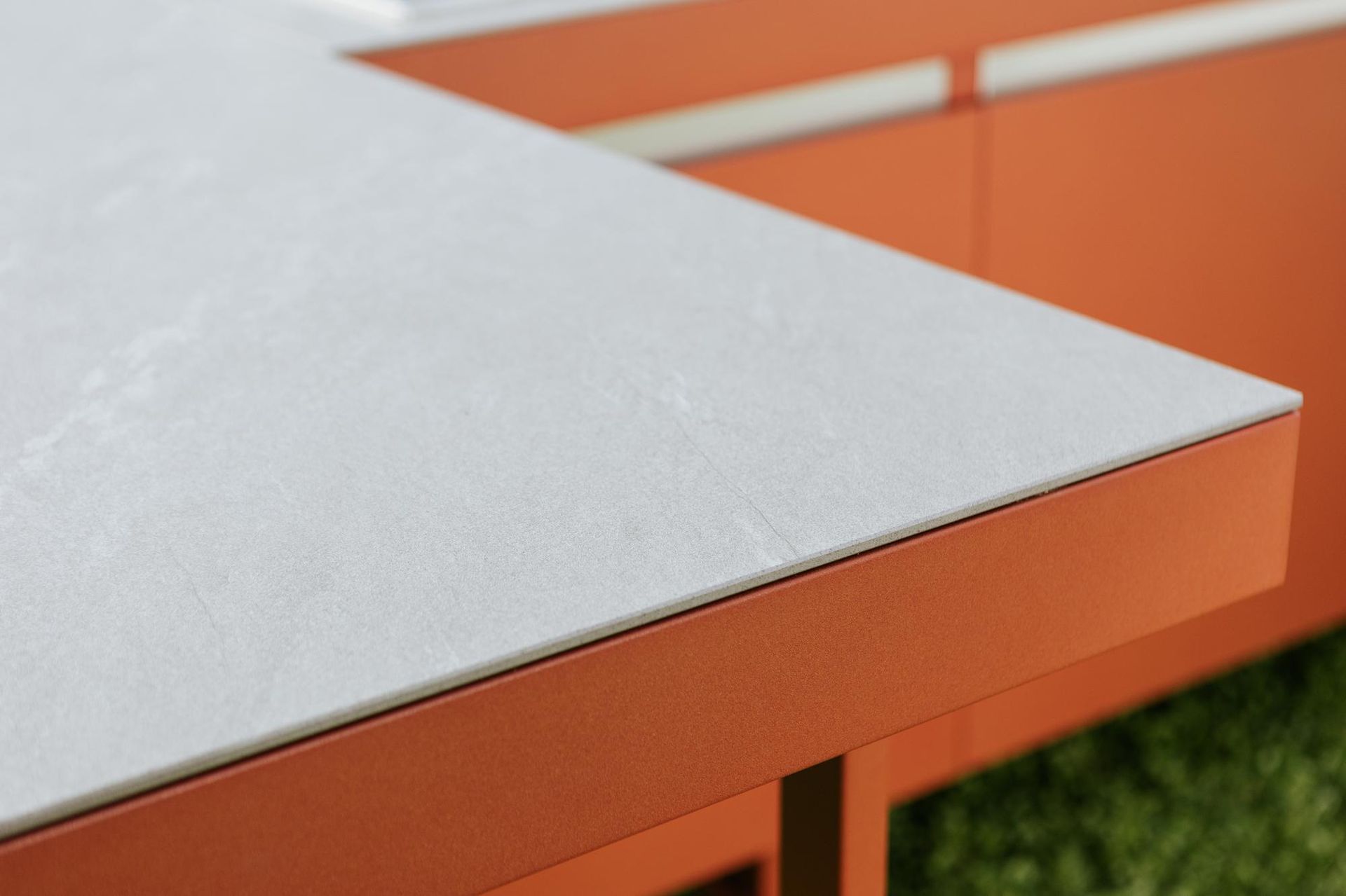 Primo piano di un piano di lavoro bianco con superficie strutturata su una struttura metallica arancione.