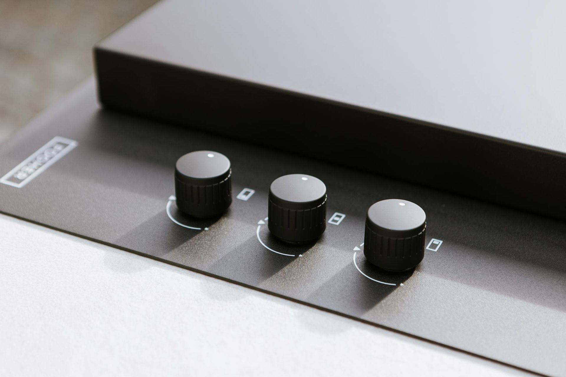 Tre manopole nere su una superficie grigio scuro, parte di un dispositivo audio.