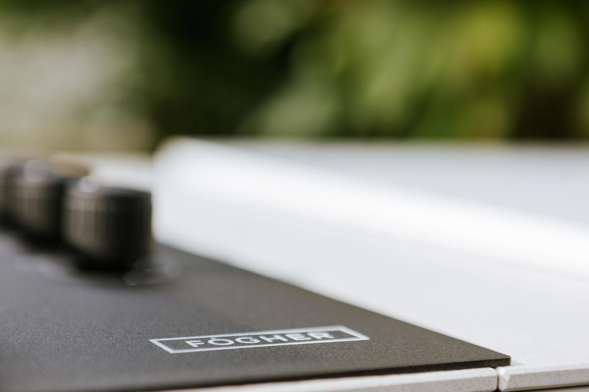 Primo piano di un pannello di controllo nero con manopole e superficie bianca, all'esterno.