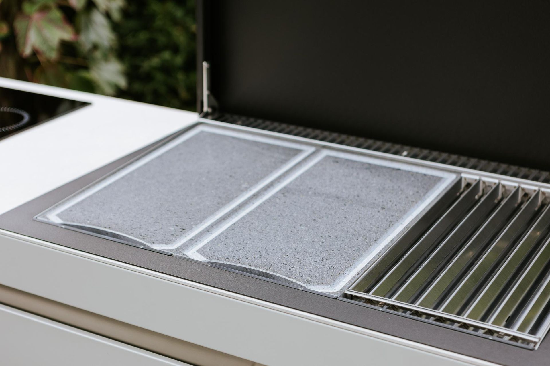 Primo piano di un moderno barbecue da esterno con due solide superfici di cottura e una griglia.