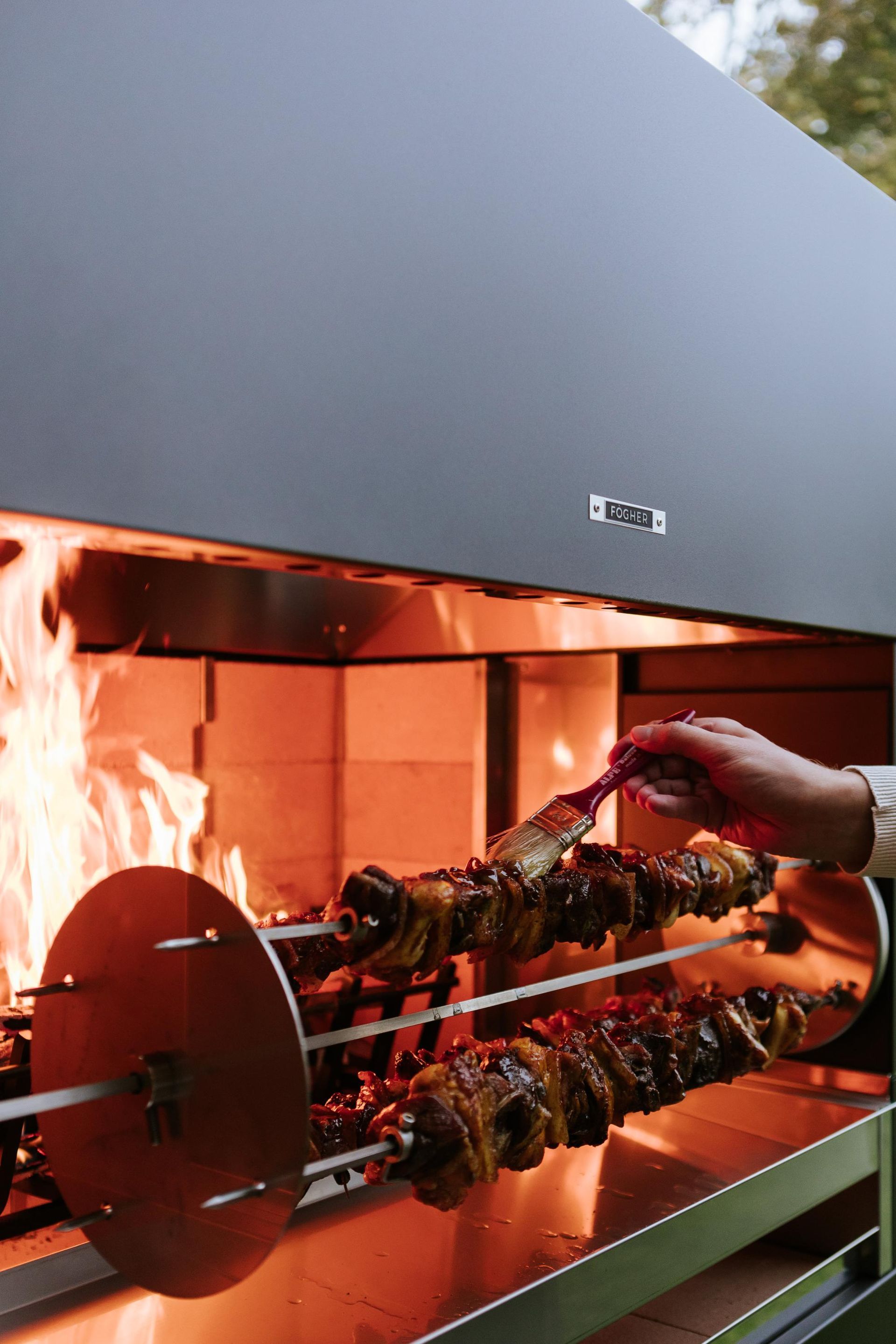 Arrostire la carne su una griglia girevole, con fuoco vivo e una mano che si prende cura del cibo.