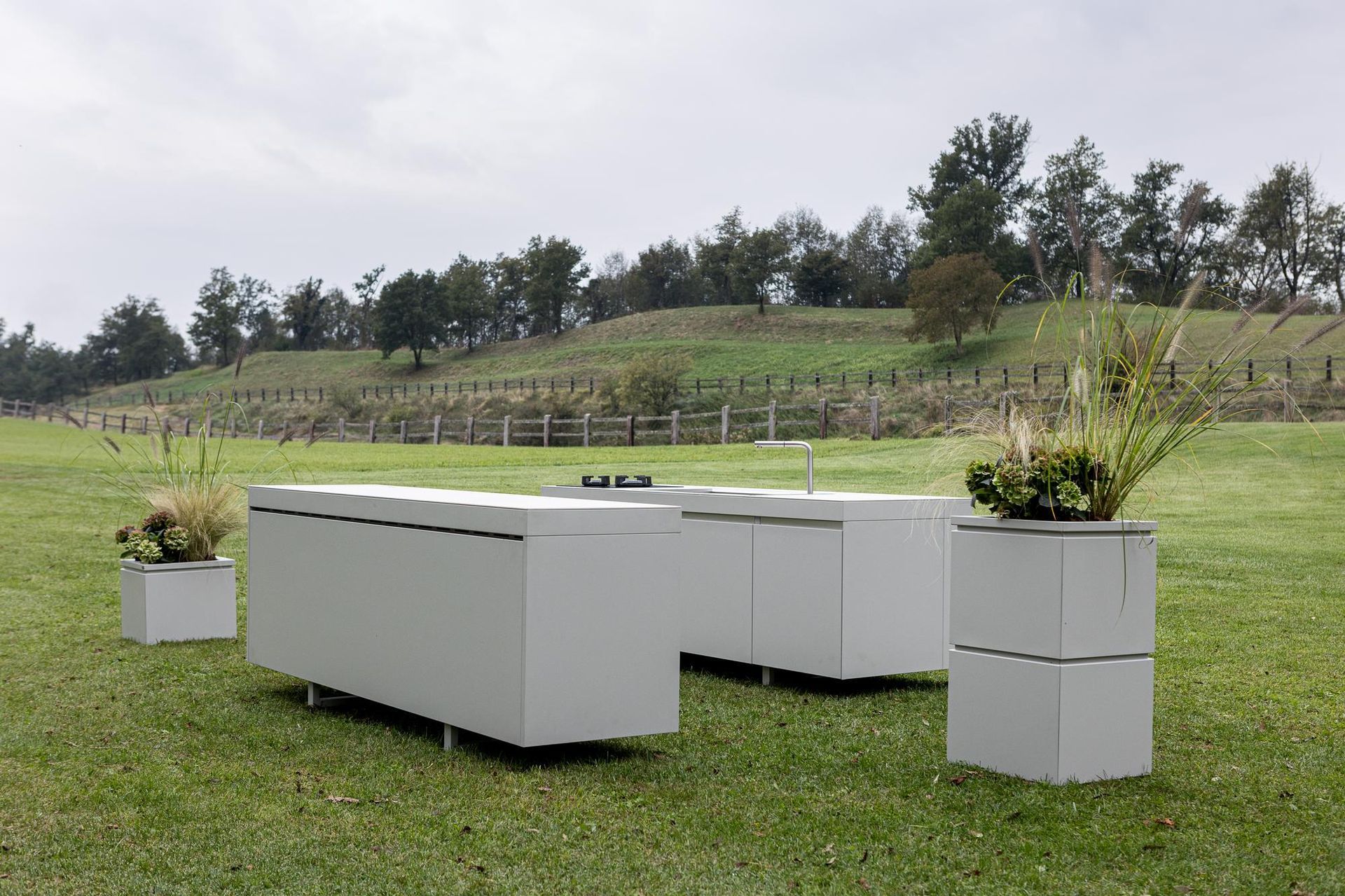 Cucina all'aperto e fioriere su un campo erboso con vigneto sullo sfondo.