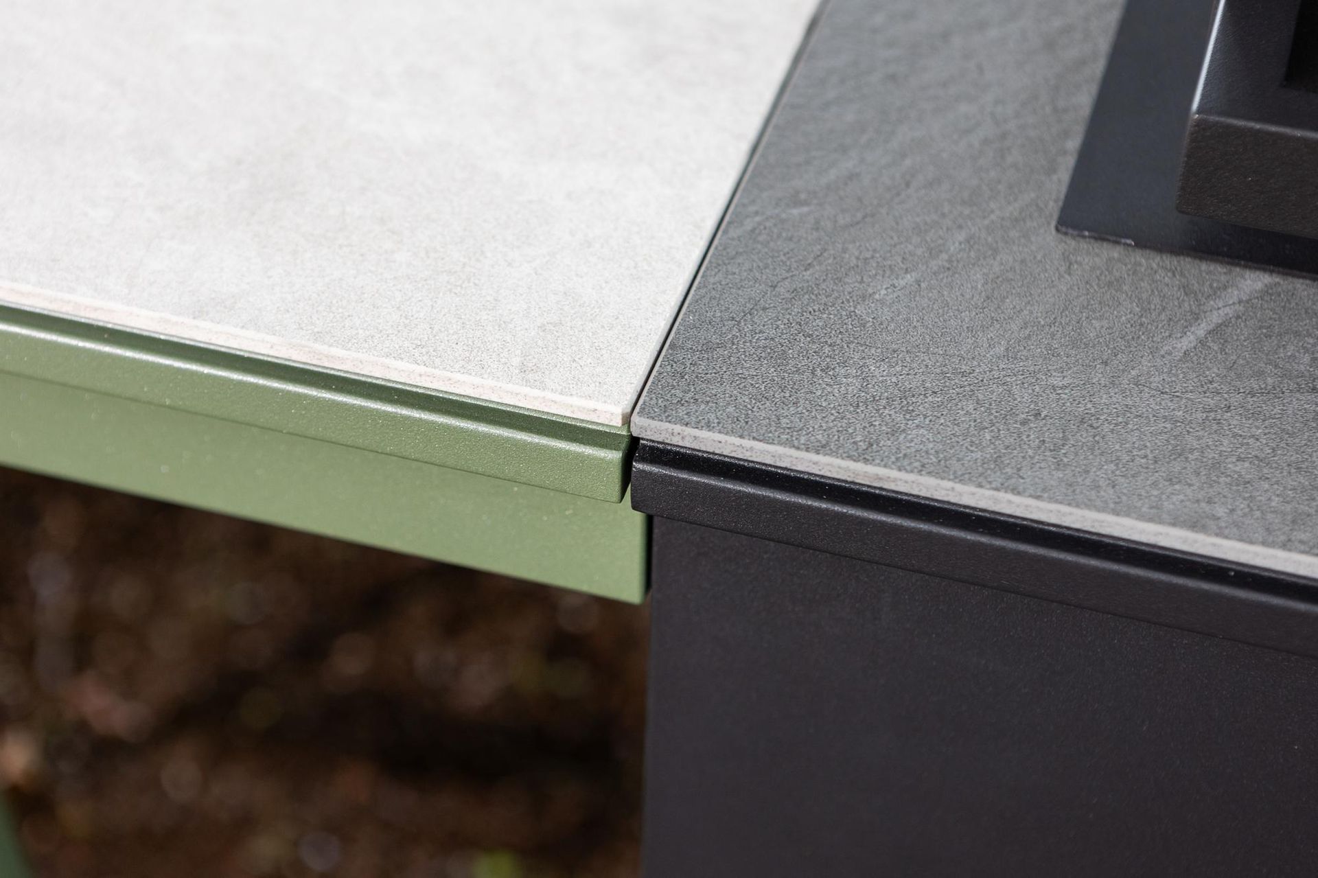 Primo piano di due tavoli da esterno con superfici di colori e texture diversi e strutture in metallo.