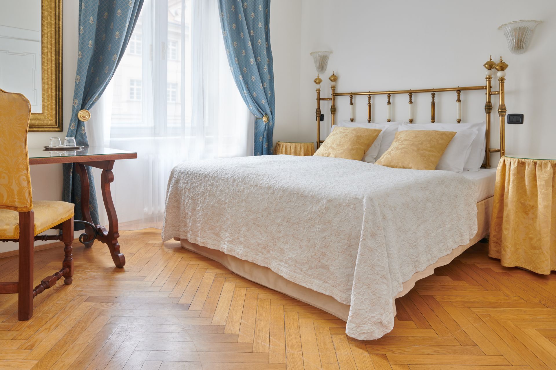 Bedroom with a bed, nightstands, a desk, curtains, and wooden floor.