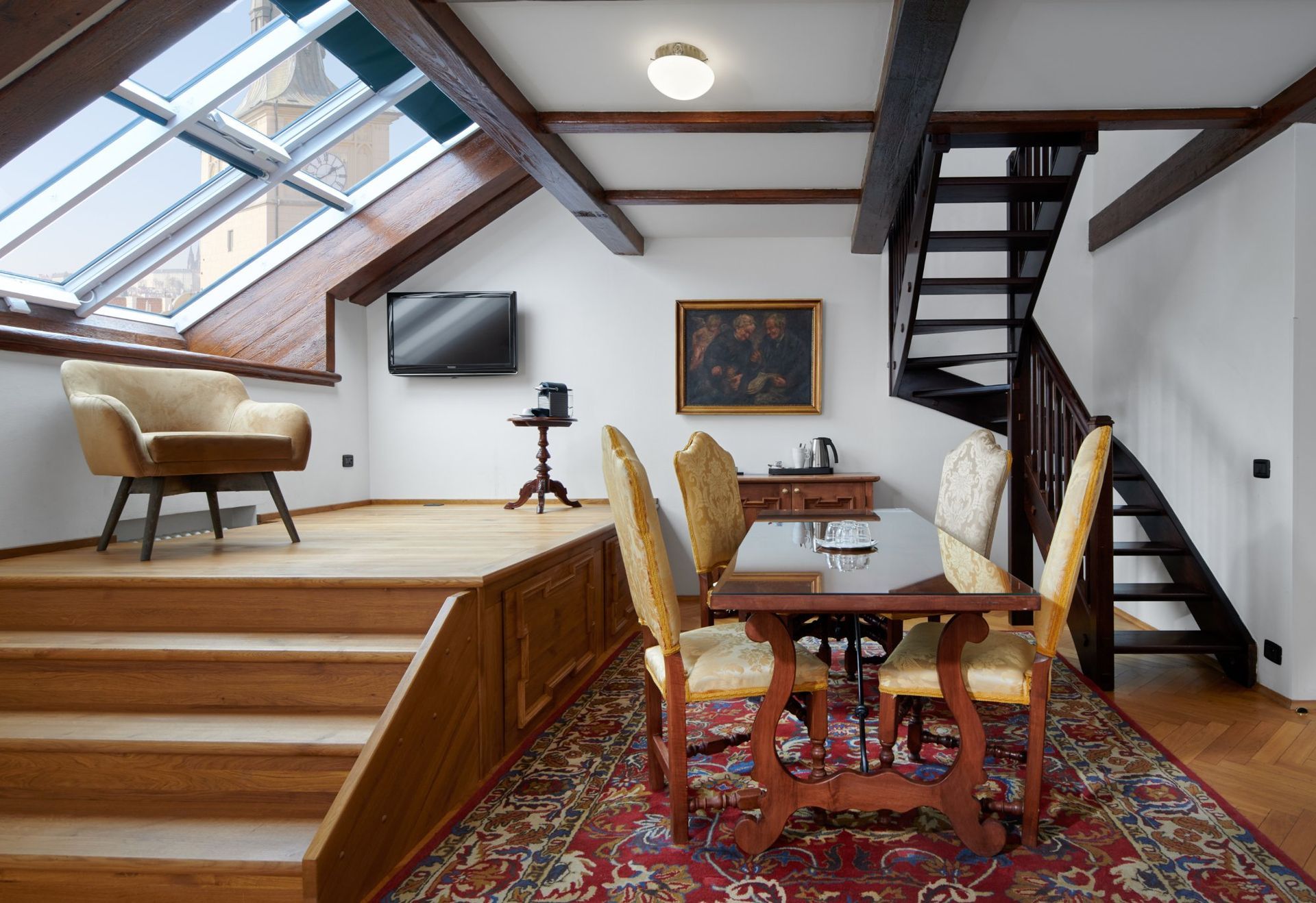 Room with dining area, armchair by a skylight, and stairs leading to an upper level with a second set of stairs.