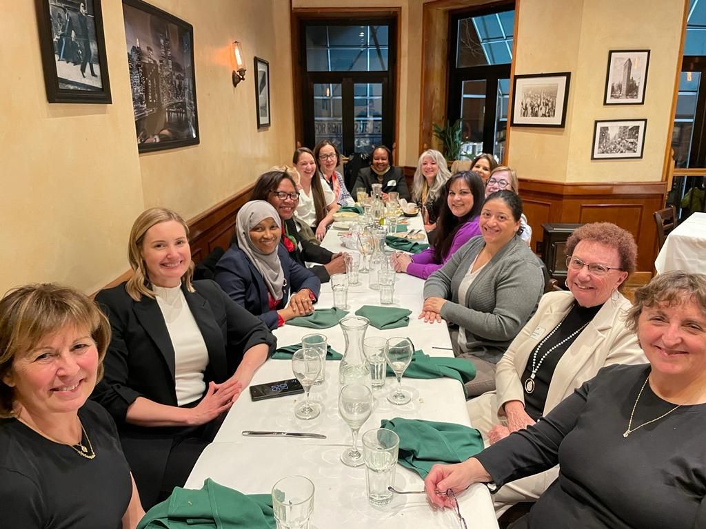a woman is sitting at a desk with a laptop and writing in a notebook .